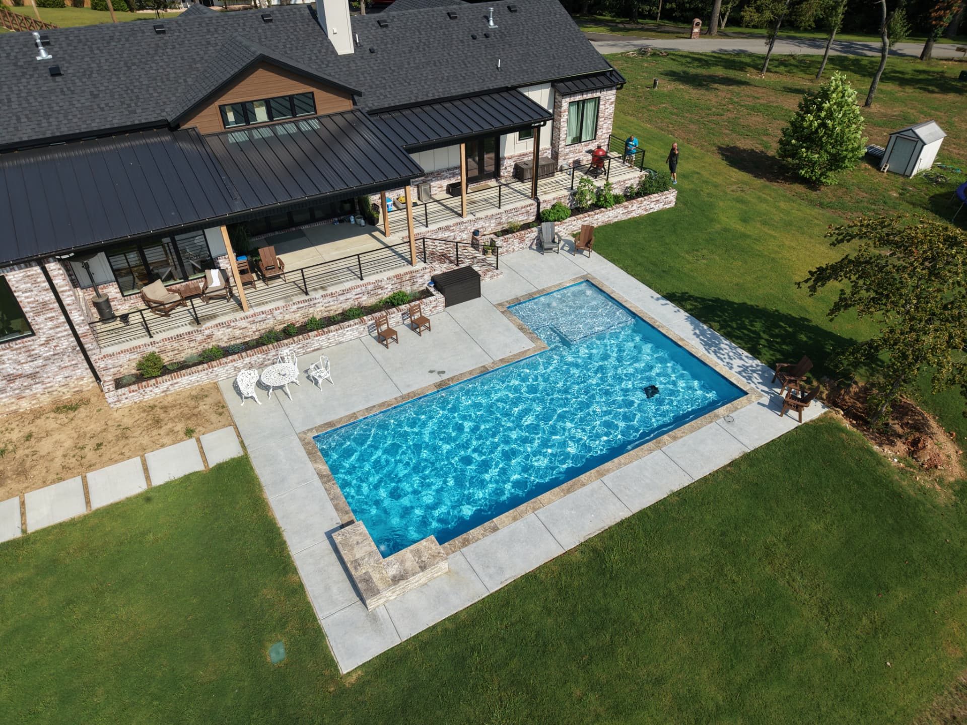 L-shaped gunite pool with a corner spa behind a large family home