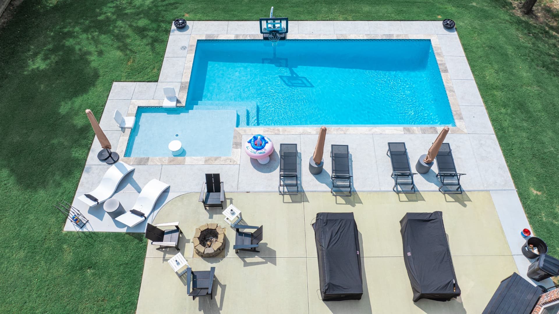 Rectangular gunite pool with a square spa, sun loungers, and a fire pit seating area